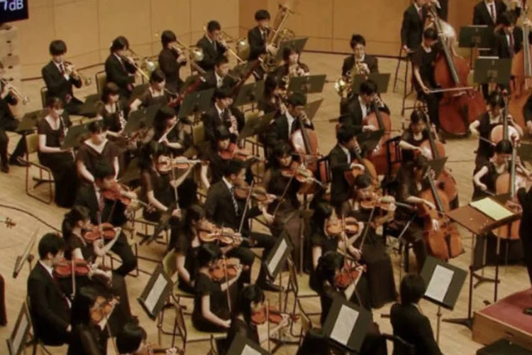 Na primeira tentativa, somos levados a acreditar que a tarefa é impossível. Mas, em seguida, a música começa a ser executada em um tom quase que inaudível, sob o olhar atento do maestro (Reprodução)