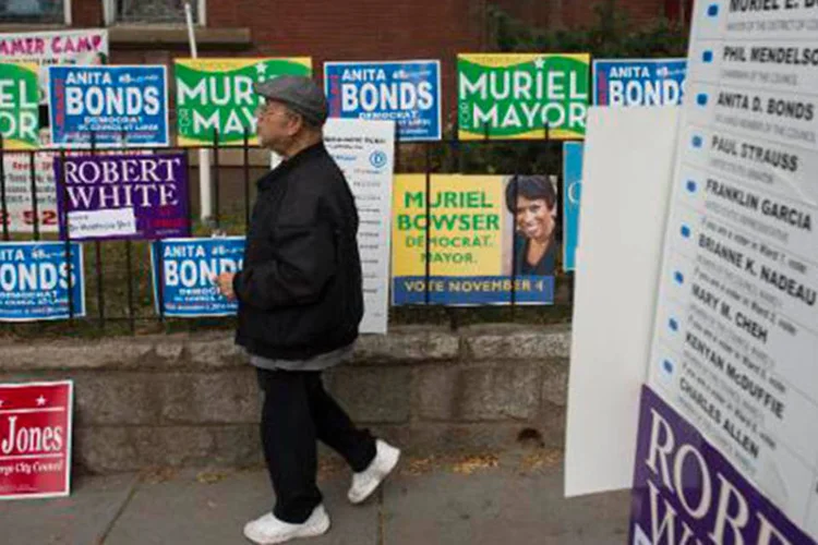Eleitor passa por cartazes da campanha em Washington, DC
 (Saul Loeb/AFP)