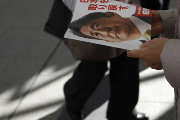Eleitor japonês segura panfleto de campanha do candidato Shinzo Abe: a campanha eleitoral, que terminará amanhã, enfocou principalmente questões econômicas (REUTERS)