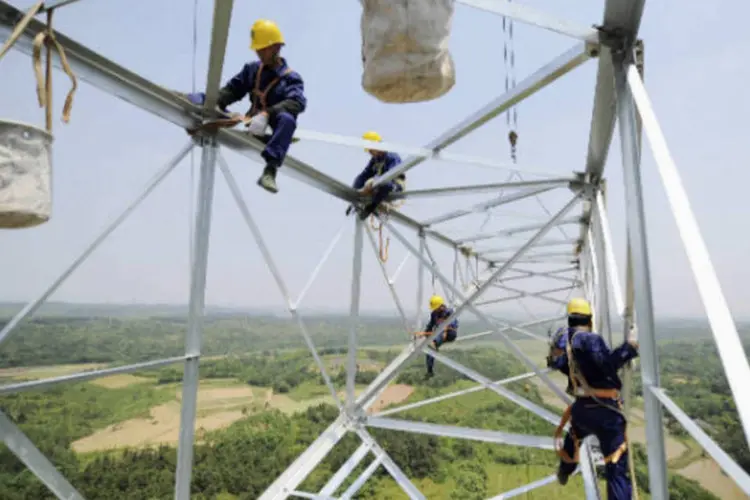 
	Trabalhadores reparam torre de eletricidade: o governo anunciou que deve assegurar a redu&ccedil;&atilde;o m&eacute;dia de 20% nas tarifas de energia em 2013
 (REUTERS/Stringer/Files)