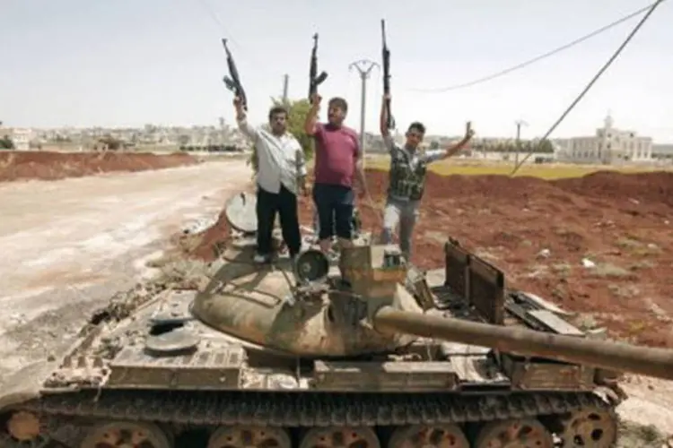 Rebeldes sírios posam em cima de um tanque: Exército Livre Sírio se retirou do bairro de Salah ad-Din por "motivos estratégicos" perante ofensiva de tropas governamentais (©AFP / Ahmad Gharabli)