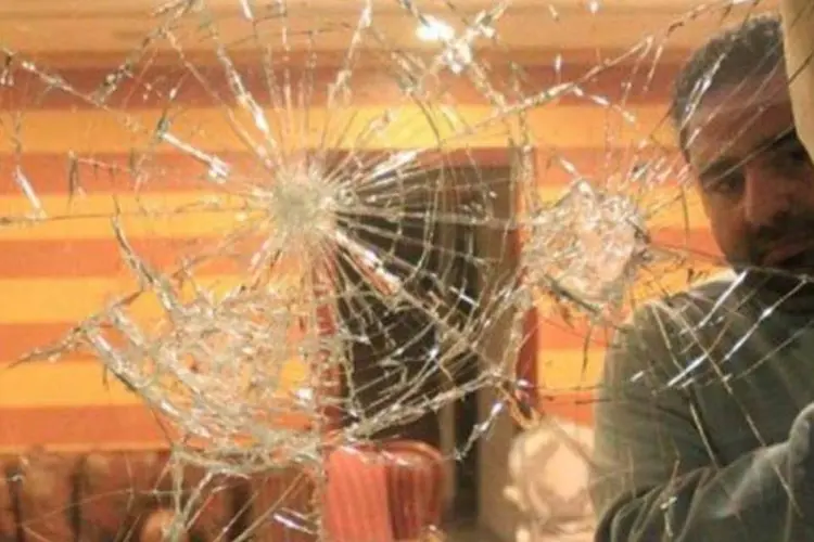 Um funcionário da embaixada síria mostra uma janela atingida por objetos após o ataque (Khaled Desouki/AFP)