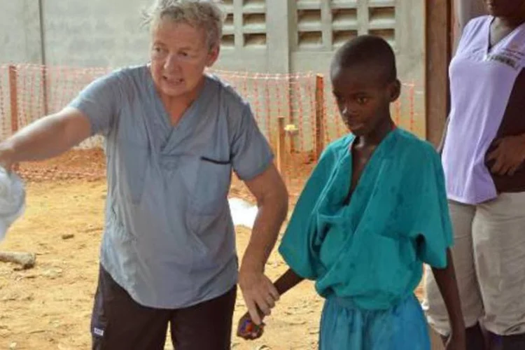Um menino de 10 anos que perdeu a mãe, infectada pelo vírus Ebola, caminha com uma missionária, após ser liberado da quarentena, na capital liberiana, Monróvia (Zoom Dosso/AFP)