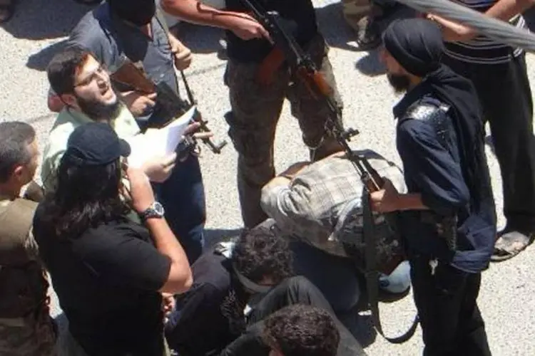 Rebeldes se preparam para matar dois homens supostamente indiciados por uma corte islâmica, na província síria de Idlib (Amr Radwan Al-Homsi/AFP)