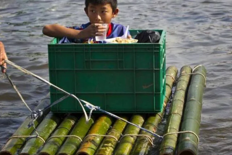 Criança é transportada em um barco na enchente da Tailândia (Paula Bronstein/Getty Images)