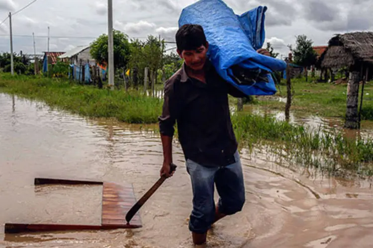 
	Homem carrega pertences em rua alagada na Bol&iacute;via: a estimativa &eacute; que 46.800 fam&iacute;lias j&aacute; tenham sido afetadas pelas chuvas
 (REUTERS/David Mercado)