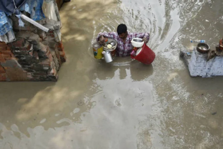 Homem carrega pertences após enchente que atingiu sua casa em em Nova Delhi, na Índia (REUTERS/Anindito Mukherjee)