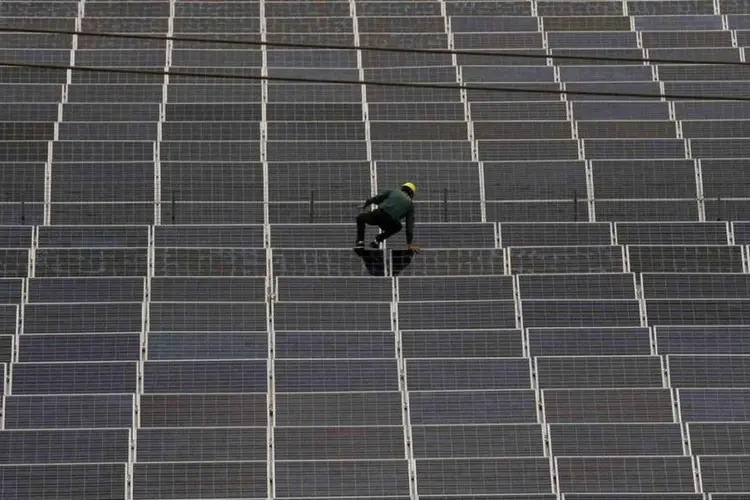 Trabalhador sobe em um painel de uma usina de energia solar, na China (William Hong/Reuters)