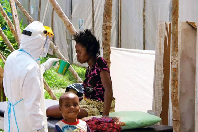 Trabalhador totalmente protegido oferece água a mulher com ebola em centro de tratamento de Kenema (Jo Dunlop/Unicef/Divulgação via Reuters)