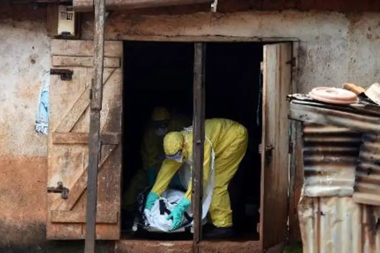 
	Profissionais da Cruz Vermelha que trabalham com v&iacute;timas do ebola retiram cad&aacute;ver de casa, em Serra Leoa
 (Francisco Leong/AFP)