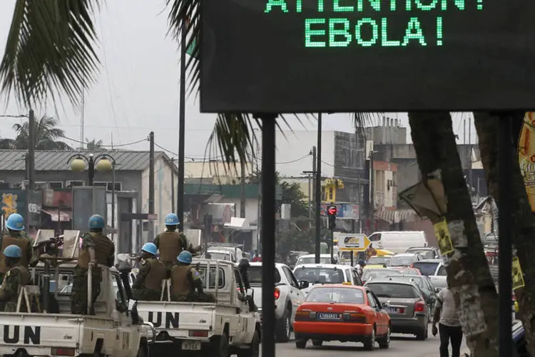Soldados da ONU passam por um letreiro eletrônico que alerta para o surto de ebola, na Costa do Marfim (Luc Gnago/Reuters)
