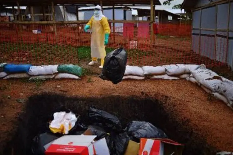 
	Membro da ONG M&eacute;dicos Sem Fronteiras lan&ccedil;a em fossa saco com objetos contaminados pelo ebola
 (Carl de Souza/AFP)