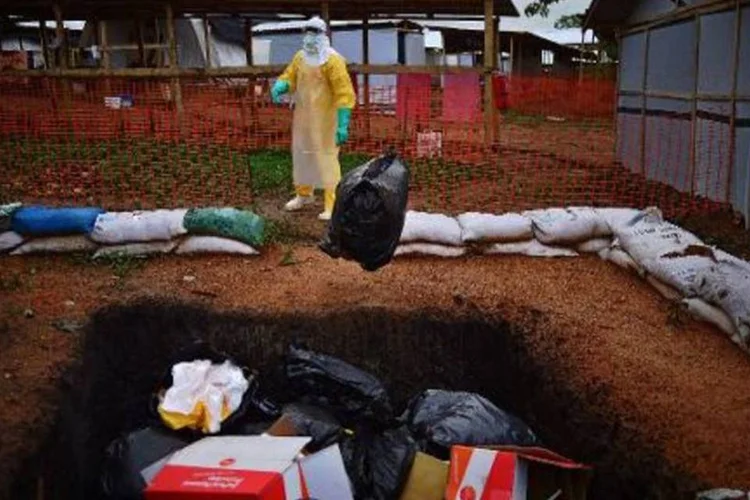 Membro da ONG Médicos Sem Fronteiras lança em fossa saco com objetos contaminados pelo ebola (Carl de Souza/AFP)