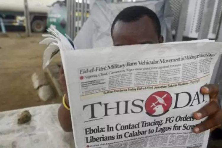Homem lê jornal com machete sobre o esforço para conter a epidemia de ebola que assola o continente africano, em 27 de julho de 2014 (Pius Utomi Ekpei/AFP)