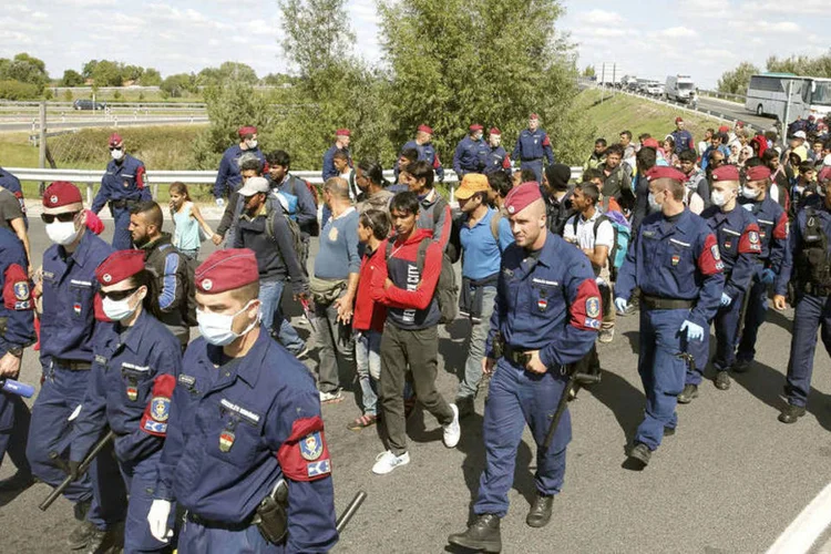 
	Escolta de migrantes pela pol&iacute;cia h&uacute;ngara voltando para ponto de inspe&ccedil;&atilde;o: refugiados fugiram em todas as dire&ccedil;&otilde;es e alguns se dirigiram para uma autoestrada que foi posteriormente fechada pela pol&iacute;cia
 (Reuters / Marko Djurica)