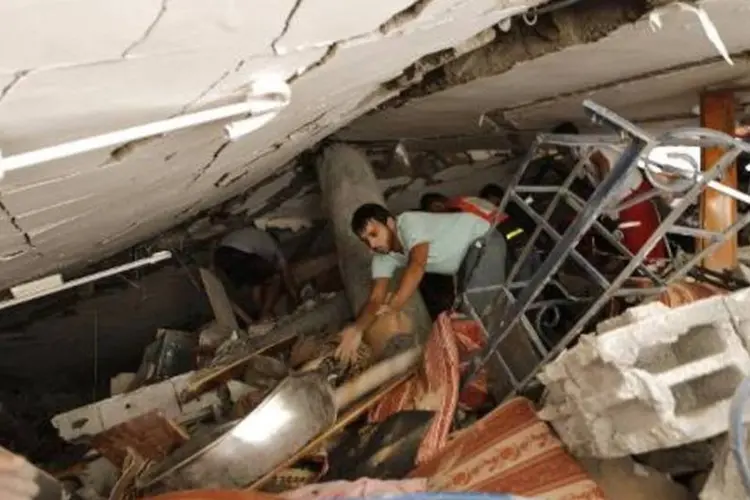 Socorristas e civis procuram vítimas nos escombros de um prédio de Gaza (Mohammed Abed/AFP)