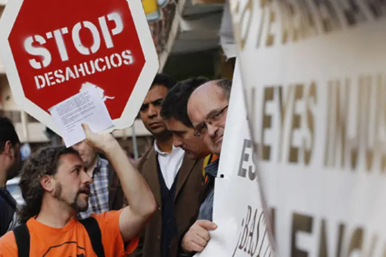 Um manifestante segura um cartaz onde se lê "parem as expulsões" do lado de fora da casa de Juan Ganan e Lucena Engracia, ameaçados de despejo (Heino Kalis/Reuters)