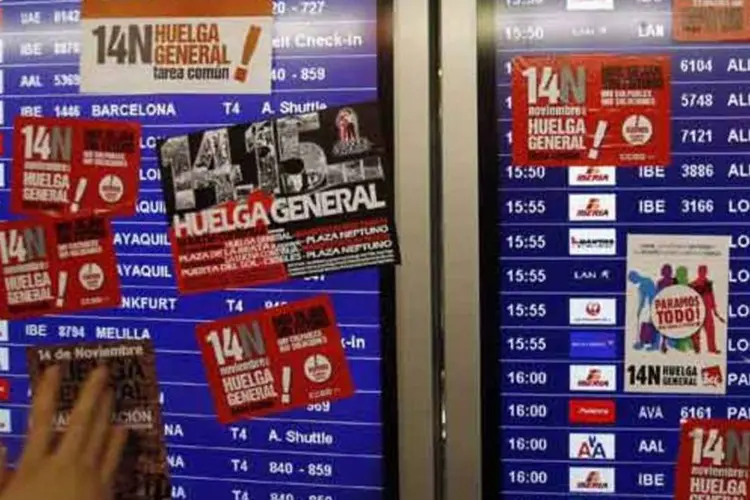 Manifestante cola adesivos no painel de informações do aeroporto de Barajas, em Madri, em 14 de novembro de 2012 (Sergio Perez / Reuters)