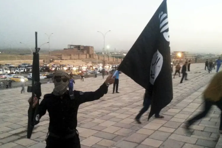 Militante do Estado Islâmico levanta bandeira e segura arma na rua de Mossul, no Iraque, dia 23/06/2014 (Reuters)