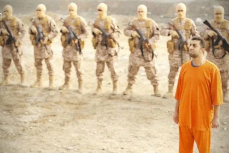 O refém jordaniano Maaz al-Kassasbeh (D) em pé diante de homens armados, em vídeo do Estado Islâmico (Social media via Reuters)