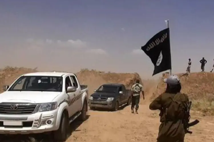 Militante do Estado Islâmico na Síria agita a bandeira da Jihad na fronteira com o Iraque (AFP)