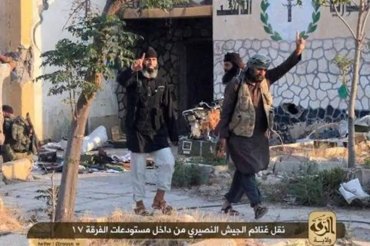 Uma imagem divulgada pela mídia jihadista mostra supostos membros do Estado Islâmico (EI) saqueando munição de uma base do exército sírio, em Raqa (AFP)