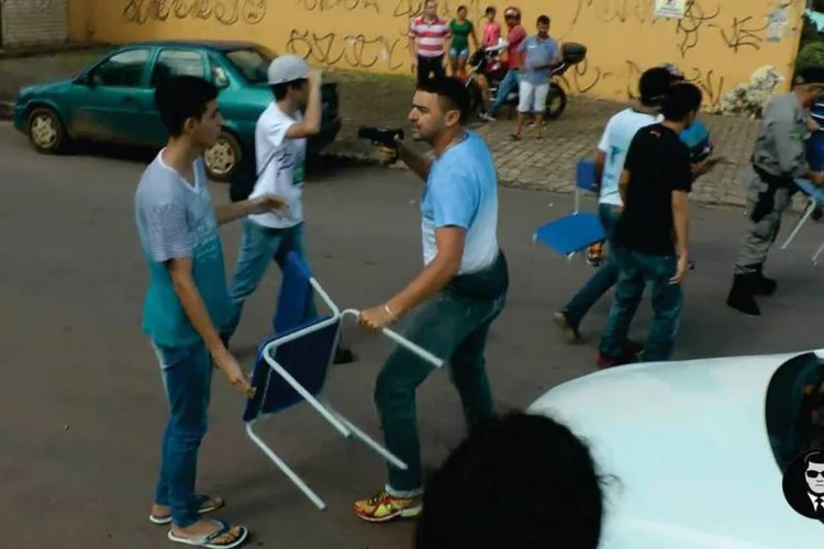 
	Protesto estudantil em Goi&acirc;nia: policial descaracterizado aponta arma para jovem com cadeira escolar
 (Reprodução/Facebook)