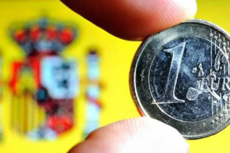 
	Moeda de euro na frente da bandeira da Espanha
 (Philippe Huguen/AFP)