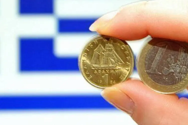 
	Moedas de euro em frente &agrave; bandeira grega: a meta &eacute; garantir as necessidades correntes do pa&iacute;s
 (©AFP / Philippe Huguen)