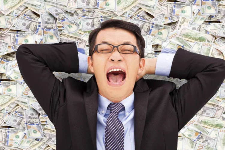 Executivo deitado em notas de dólar: na lista empresas com salário médio de 100 mil dólares anuais (Thinkstock)
