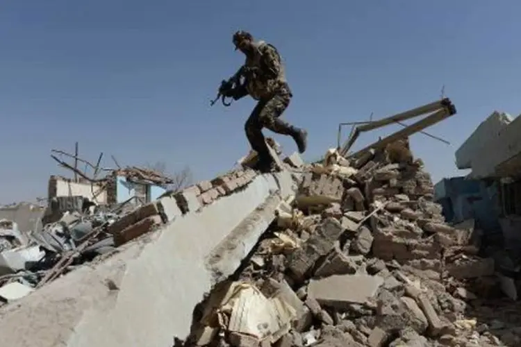 Soldado afegão nos escombros do local de um ataque suicida a um complexo do governo, na cidade de Ghazni (Shah Marai/AFP)