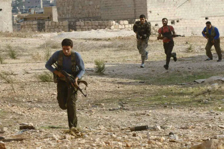 Membros do Exército Sírio Livre correm com suas armas durante confrontos na Síria (Stringer/Reuters)