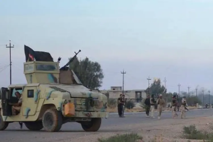 Forças ligadas ao governo iraquiano em estrada durante operação contra EI (Younis Al Bayati/AFP)