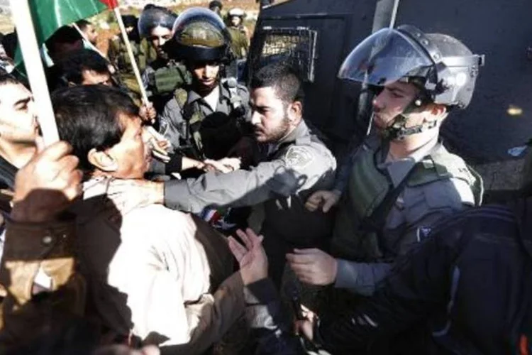 Guarda de fronteira israelense segura o dirigente palestino Ziad Abu Ein (E) durante protesto em Turmus Aya (Abbas Momani/AFP)