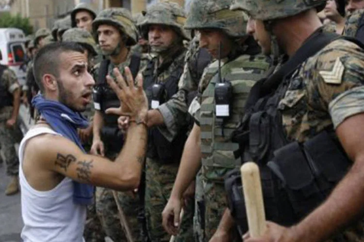 
	Um membro do movimento anti-S&iacute;ria 14 de mar&ccedil;o discute com membros da for&ccedil;a de seguran&ccedil;a libanesa: tr&ecirc;s morreram e dezenas ficaram feridos em choques entre manifestantes
 (AFP)