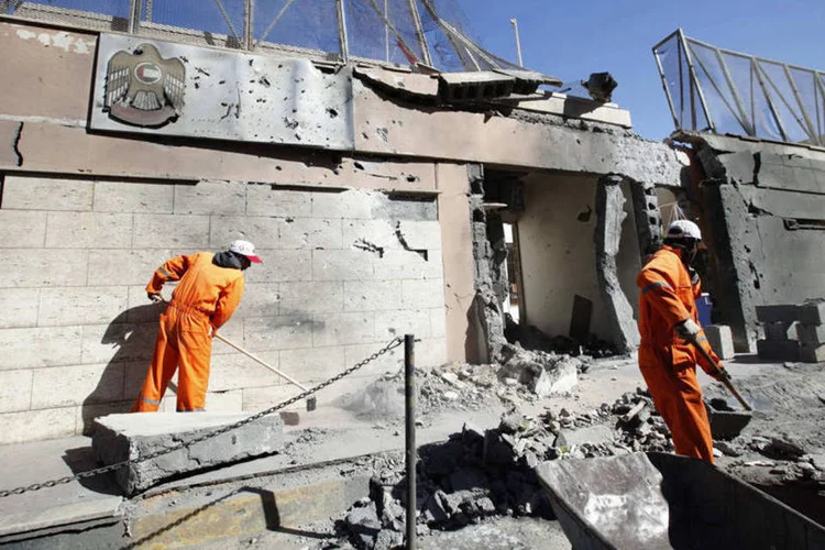 Funcionários limpam os destroços após a explosão de um carro-bomba na embaixada dos Emirados Árabes na Líbia (Ismail Zitouny/Reuters)