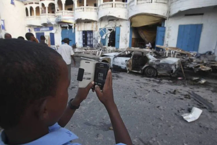 Menino tira uma foto do local da explosão de um carro-bomba, em frente a um restaurante de Mogadíscio (Omar Faruk/Reuters)