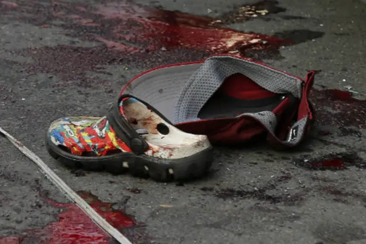 Sapato e boné em local com manchas de sangue após explosão na Tailândia: garota é a irmã mais velha de outra criança morta durante o ataque (Paul Barker/Reuters)