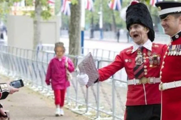 Um fã da rainha vestido de guarda real posa ao lado de militares nas imediações do Palácio de Buckingham (Miguel Medina/AFP)