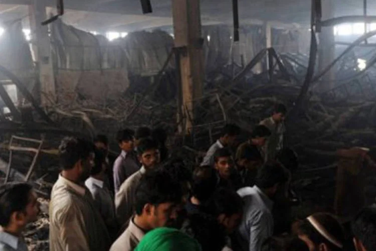 
	Pessoas observam destro&ccedil;os de f&aacute;brica em Karachi: o ambiente estava em estado calamitoso, sem ventila&ccedil;&atilde;o suficiente nem portas de emerg&ecirc;ncia
 (Rizwan Tabassum/AFP)