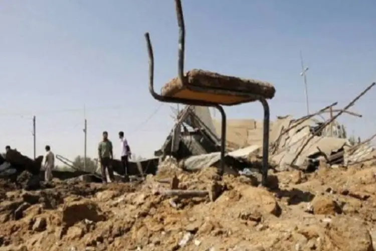 Palestinos olham os destroços deixados por um dos ataques israelenses em Khan Yunis, sul da Faixa de Gaza (AFP)