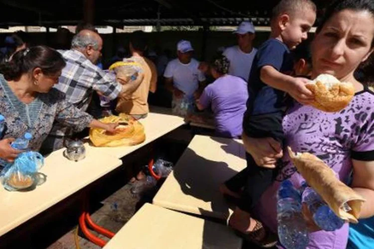 Famílias cristãs que fugiram de jihadistas recebem alimentos em Igreja no Curdistão (Safin Hamed/AFP)
