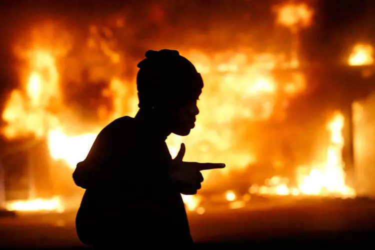 
	Homem passa em frente ao fogo durante protesto ap&oacute;s j&uacute;ri popular em Ferguson, nos EUA
 (REUTERS/Jim Young)