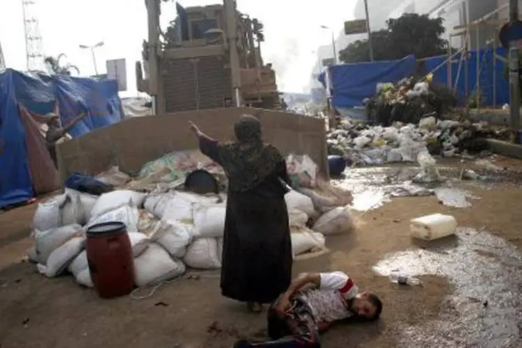 Mulher tenta conter uma escavadora militar, para proteger um ferido caído em uma rua do Cairo (Mohammed Abdel Moneim/AFP)