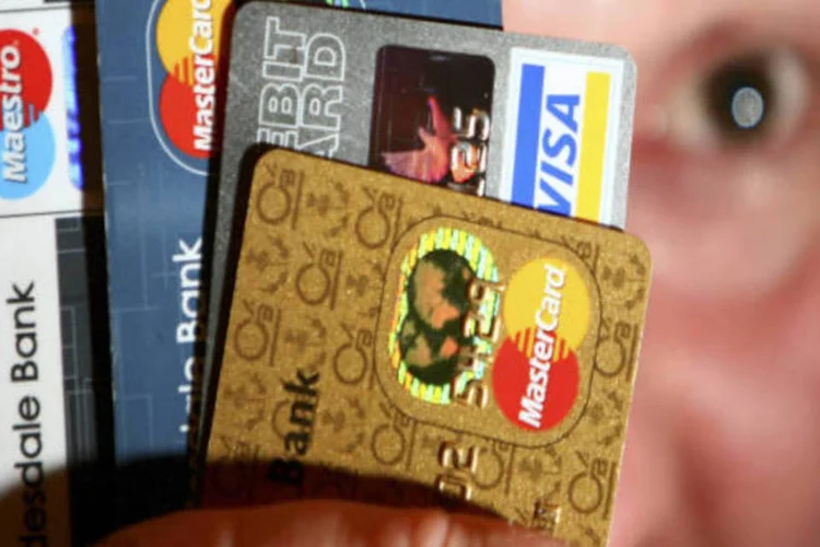 
	Homem segura v&aacute;rios tipos de cart&otilde;es de cr&eacute;ditos em suas m&atilde;os: consumidores americanos est&atilde;o mais cautelosos com seus gastos
 (GettyImages)