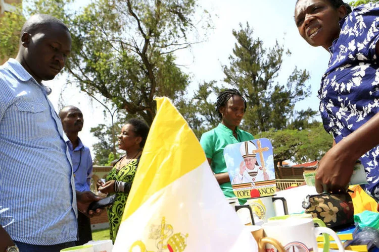 
	Fi&eacute;is de Uganda olham suvenires da visita do pont&iacute;fice: o papa foi recebido por uma delega&ccedil;&atilde;o governamental e religiosa
 (James Akena/ Reuters)