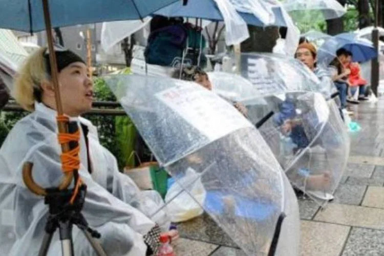 Em Tóquio, japoneses fazem fila na chuva para comprar o iPhone 4, o mais novo lançamento da Apple.  (.)