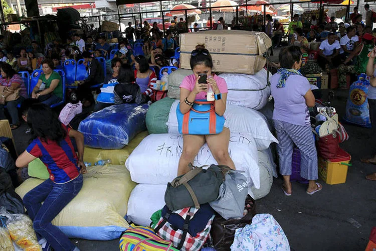 Filipinos aguardam com suas malas em rodoviária de Manila (REUTERS/Romeo Ranoco)