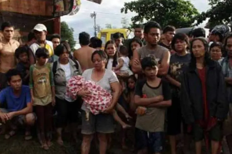 Mulher segura corpo de criança morta durante passagem de tempestade tropical em Iligan, Filipinas (Cherryl Vergeire/ AFP)