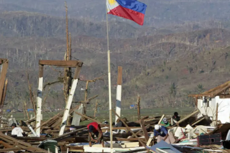 
	Bandeira das Filipinas &eacute; vista em meio a destro&ccedil;os: mais de 87 mil pessoas tiveram que buscar ref&uacute;gio em abrigos por causa das enchentes causadas pelas chuvas
 (REUTERS/Erik De Castro)
